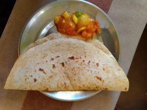

A stainless steel plate holds golden flatbread with charred spots.