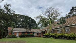 2 building blocks with a neat compound in the foreground and tall trees in the background.