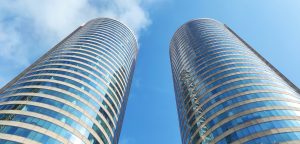 A perspective view of two tall, curved skyscrapers standing side by side, reaching toward a clear blue sky with a few scattered clouds. The World Trade Center Colombo, Sri Lanka
