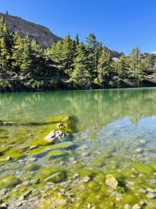 

A serene Dhumba lake reflecting blue skies and surrounding greenery. 