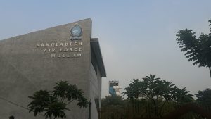 A picture of a Bangladesh Air Force Museum entrance gate with blue sky and trees.