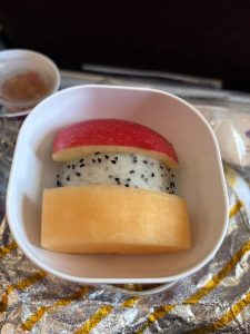 A small white cup contains three layers of fruit, arranged to resemble a dessert.