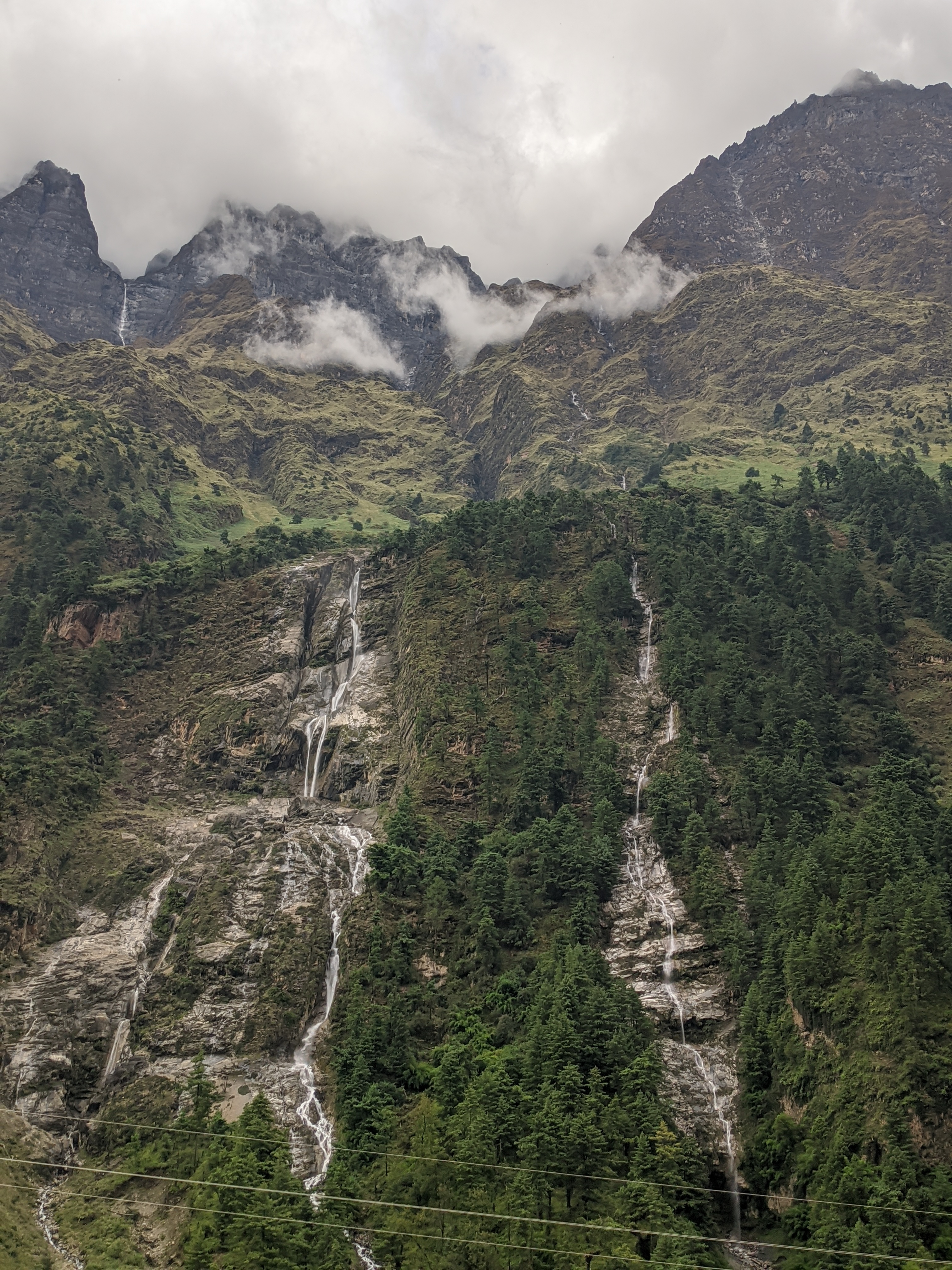 A scenic view of a mountainous landscape featuring multiple waterfalls cascading down rocky cliffs.