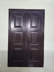 A dark brown, traditional wooden window with six raised panels. Photographed at Hill Palace, Thrippunithura, Kerala. 