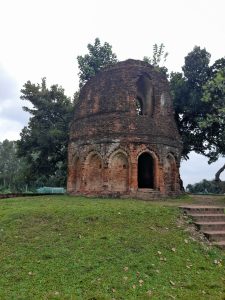 

Ancient red brick arches amid green grass and trees under a calm, cloudy sky.