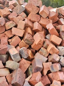 A pile of red burnt bricks in various textures and shades after firing. Captured outdoors in Perumanna, Kozhikode, Kerala. Shows the final stage of traditional brick-making.