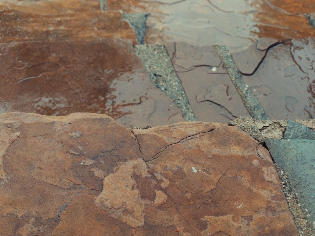 Red stone steps that are damp and wet from rain.