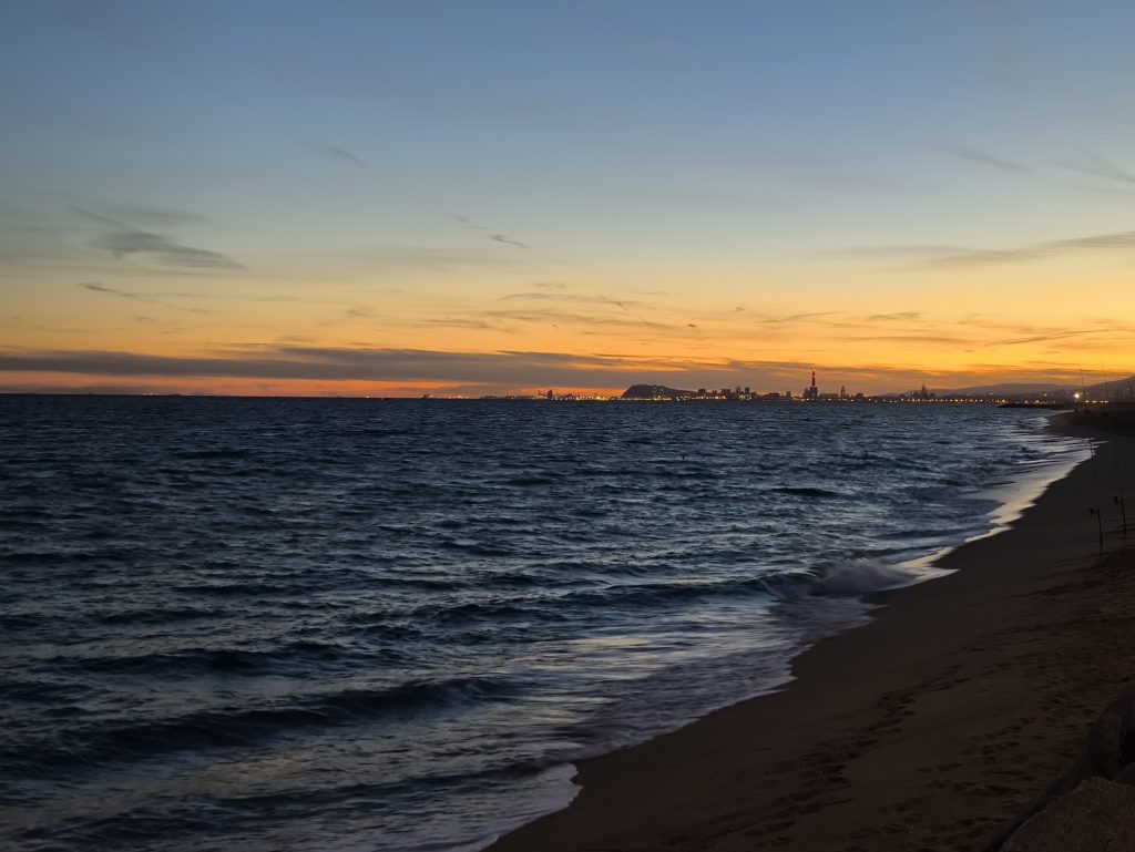 A peaceful Barcelona beach at sunset with gentle waves.