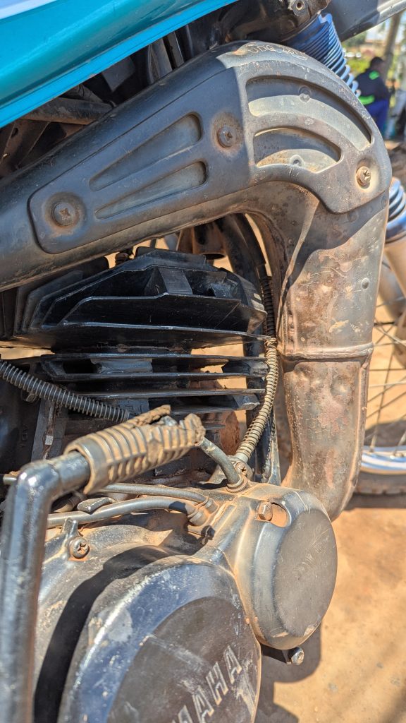 Close-up of a motorcycle engine, highlighting the cylinder, exhaust pipe, and wiring.