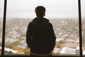 Woman looking out over the Seattle skyline from the space needle with fall colors are visible. 
