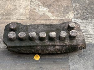 A Balipeedam or Balikallu, a weathered stone with nine round protrusions placed on a stone floor, is used for making offerings to deities or spirits. It was photographed at Sree Shiva Vishnu Temple, Perumanna, Kozhikode.