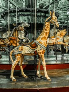 An antique carousel featuring a ride-on wooden giraffe.
