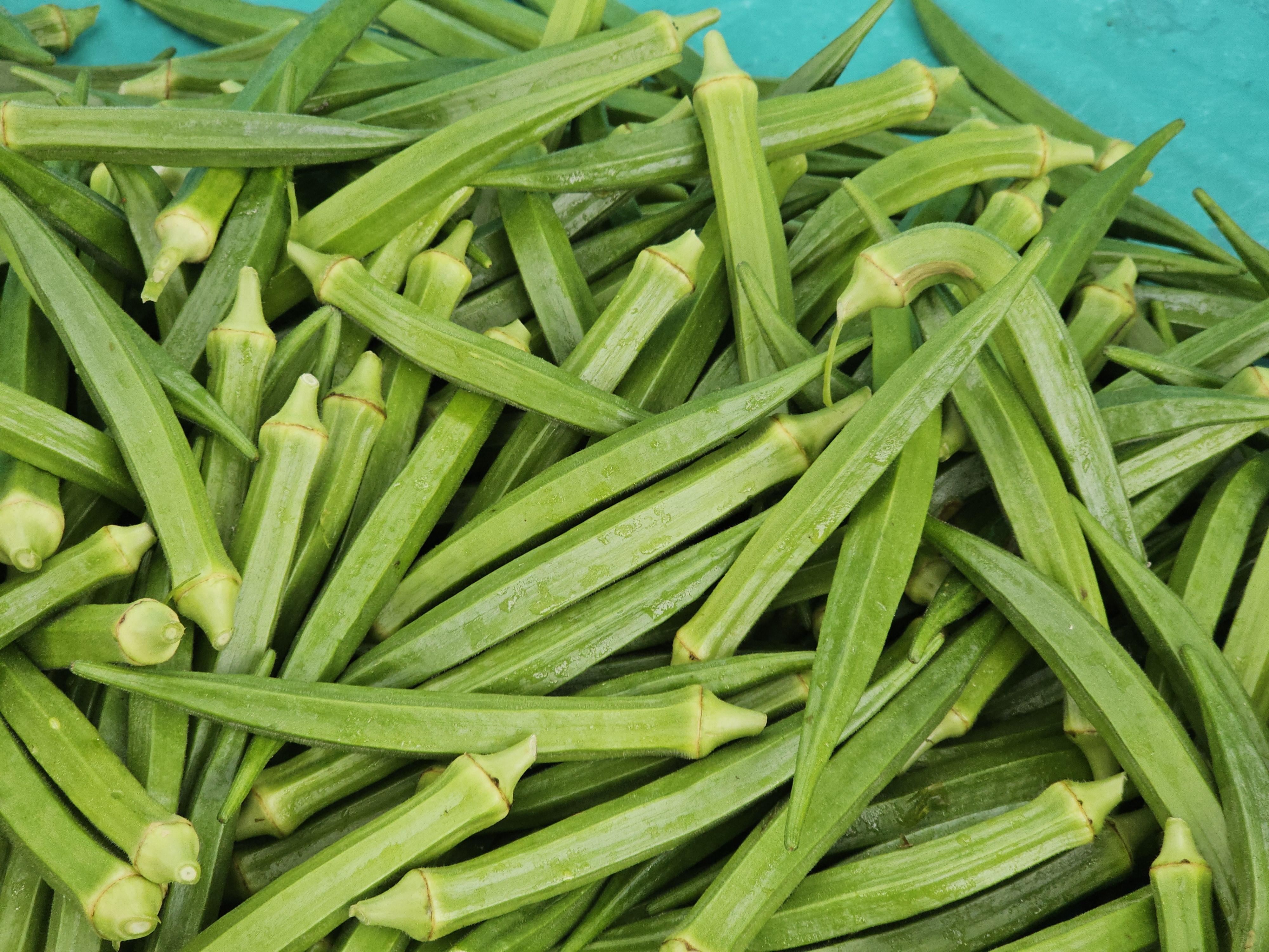 A pile of fresh okra (ladies' fingers) with bright green color and firm texture. Captured in a market from Peruvayal, Kozhikode.