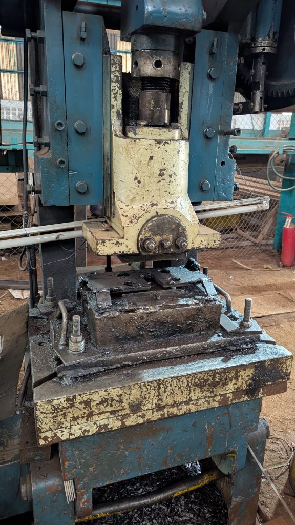 A close-up image of a heavy industrial machine part, specifically a hydraulic press or stamping machine