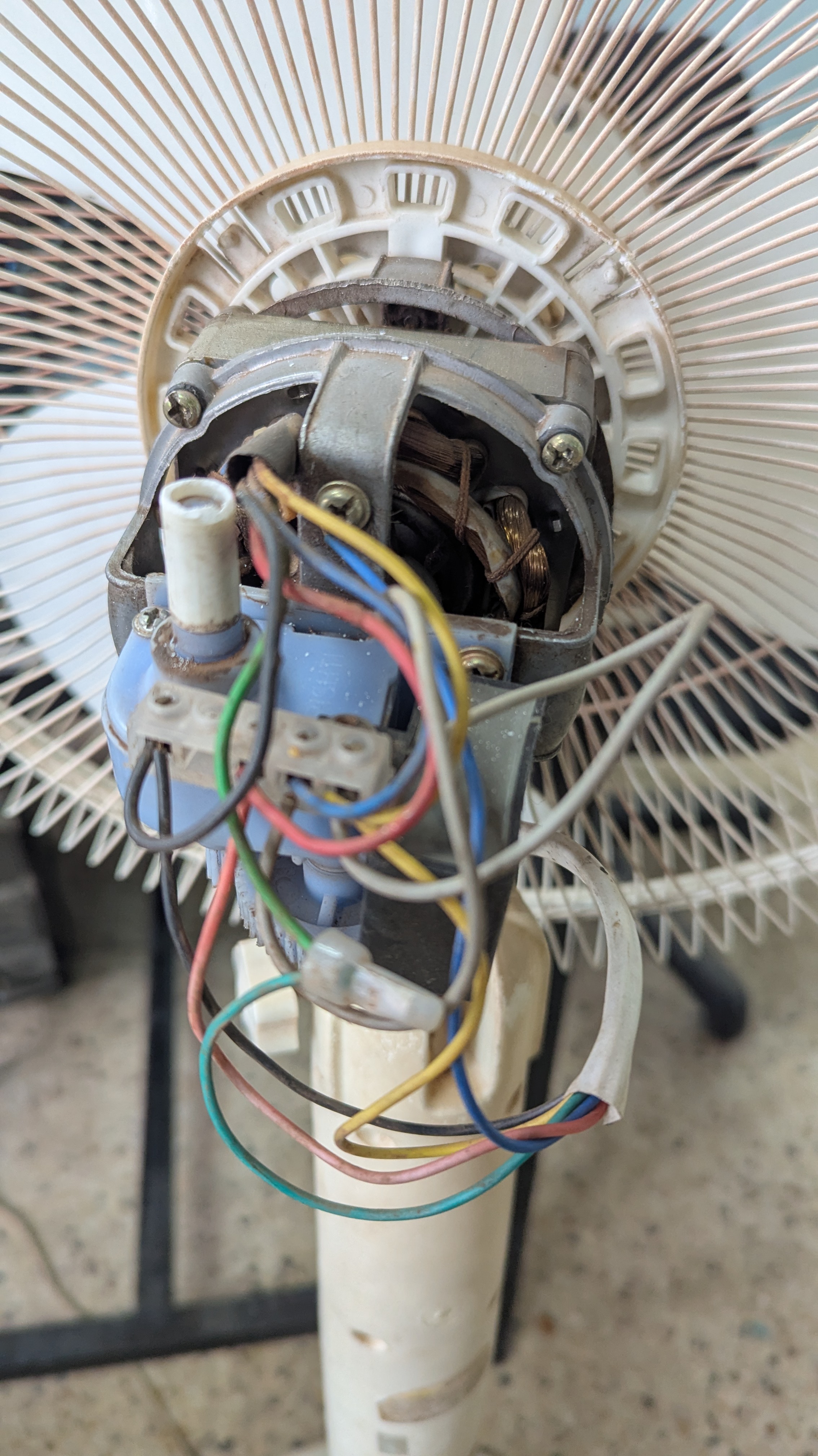 Close-up of an electric fan’s internal components, showing the motor, wiring, and connections.