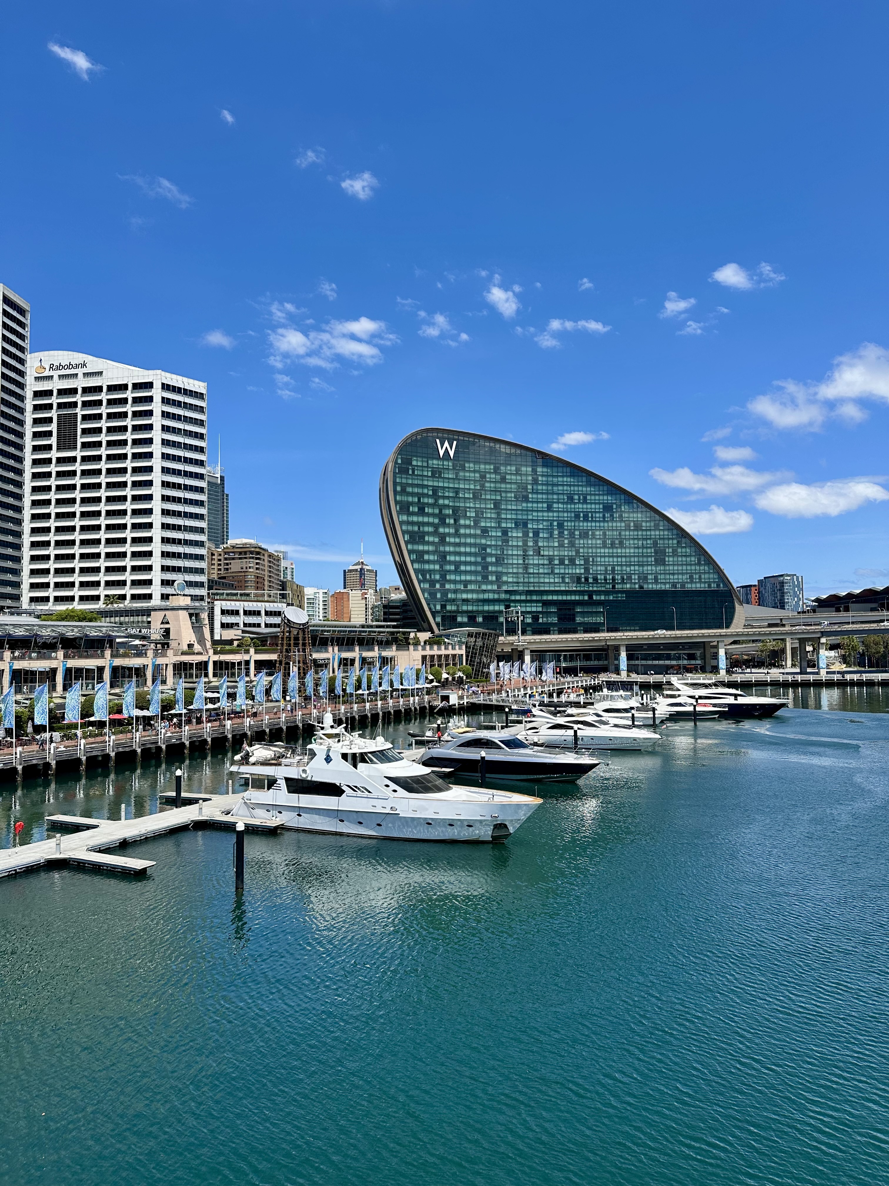 A ships is docked in a bustling harbor with the iconic W-shaped building towering behind it!