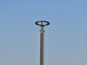 A tall solar-powered light pole stands against a clear blue sky. Its modern circular top creates a clean and straightforward scene, taken in Bandra West, Mumbai, Maharashtra.