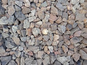 A close-up view of a variety of small, irregularly shaped stones displaying a mix of gray, brown, and reddish hues, arranged closely together on a flat surface