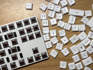 Low-profile mechanical keyboard with brown switches and keycaps being removed on a table.

