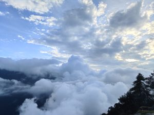 A panoramic view of a blue sky filled with fluffy white clouds, some illuminated by sunlight.