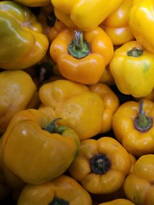 A close-up of fresh yellow bell peppers arranged in a group. Their smooth, shiny surface and bright color stand out. Captured from a market in Kozhikode, Kerala. 