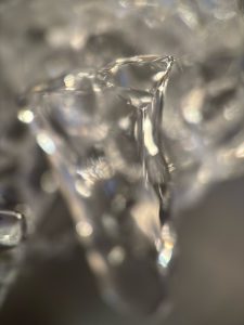 A very closeup shot of a bit of ice. The focus is on a tip, sparkling with light.
