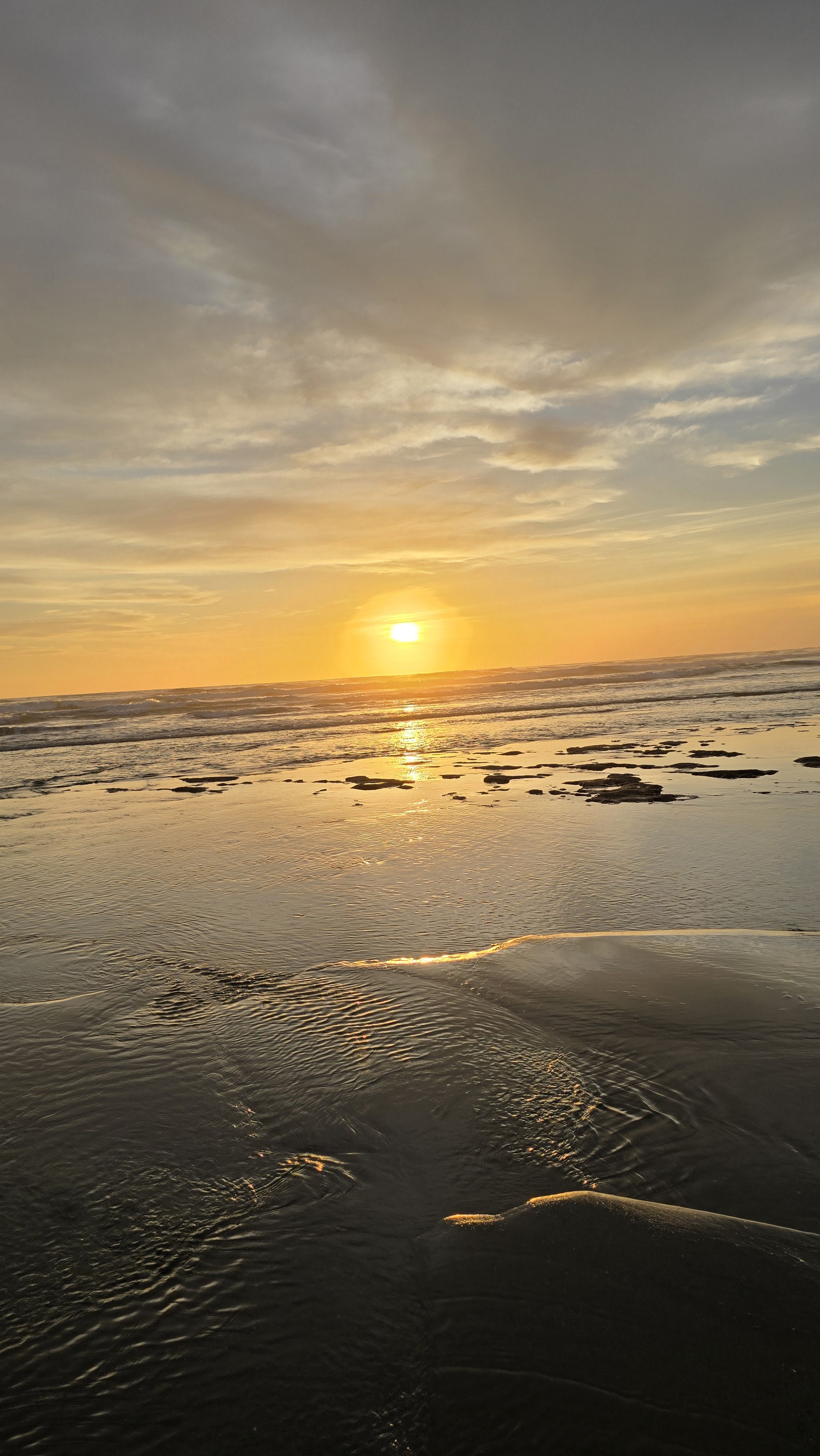 A calm sunset over Masachapa Beach, Nicaragua, with the sun glowing above the horizon.