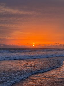 Beautiful sunrise over Kuakata Beach, where golden-orange skies reflect on gentle waves, creating a peaceful and breathtaking morning scene in Bangladesh.