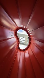 The photo looks up at the Umeda Sky Building in Osaka, Japan, through the red sculpture in front of it.