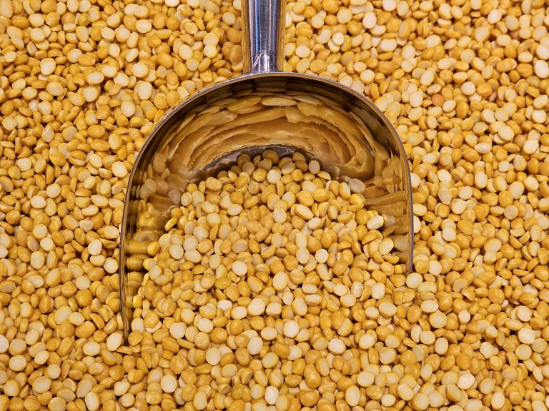 A metal scoop rests on bright yellow split dal at a hypermarket in Kozhikode. The grains shine with a warm yellow hue, making them a popular choice for everyday cooking.