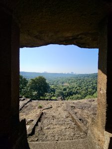 A beautiful view of the forest valley from a cave opening at Kanheri Caves, Borivali, Mumbai, framing the greenery and city skyline in the distance. 