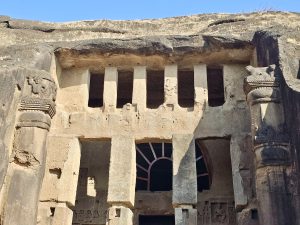 A close-up of the detailed stone pillars and carved openings of the Kanheri Caves in Mumbai, showing the skill and history of early Buddhist rock-cut architecture. 