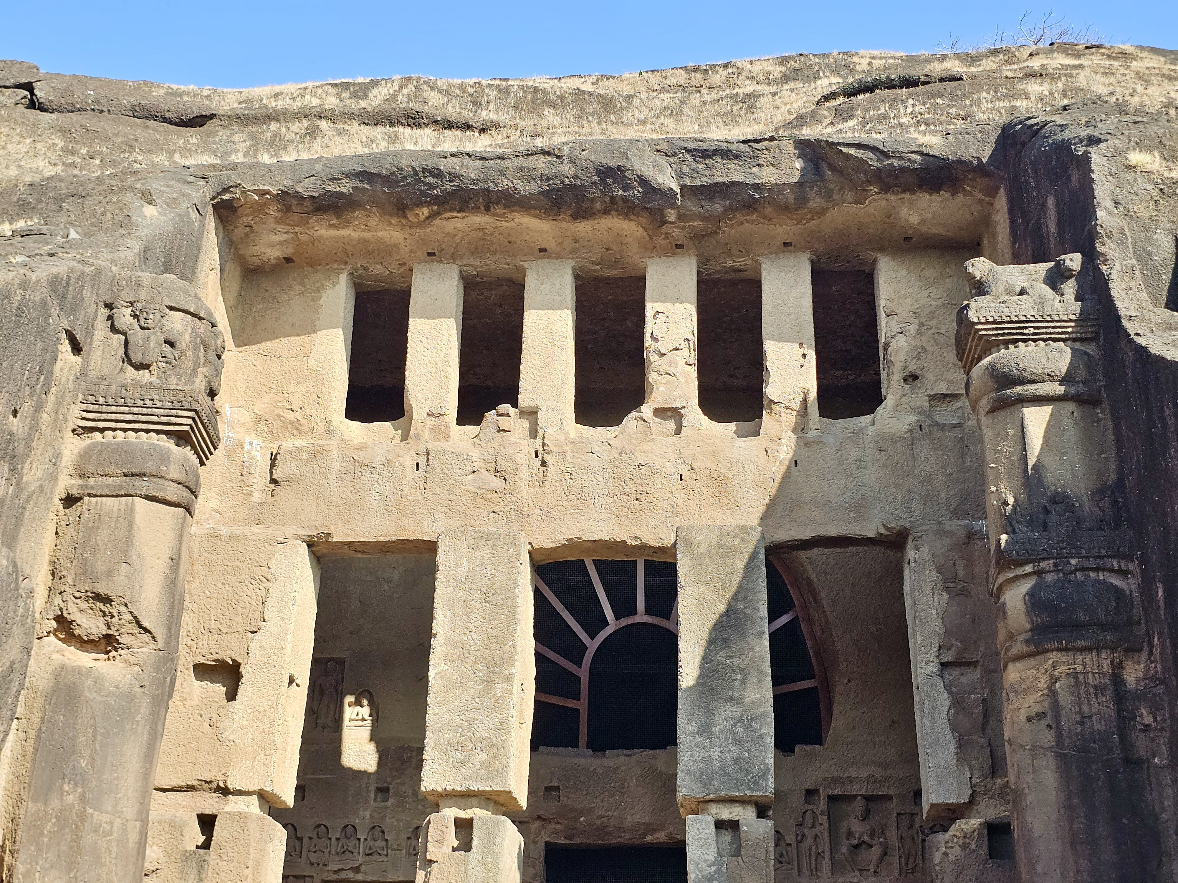 A close-up of the detailed stone pillars and carved openings of the Kanheri Caves in Mumbai, showing the skill and history of early Buddhist rock-cut architecture.