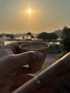 Early Morning Sunrise View and a human hand holding a cup of tea in a clay cup. 