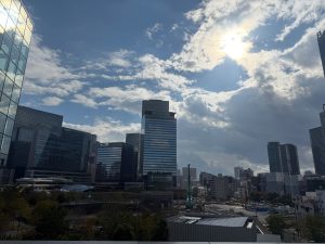 Osaka&#039;s cityscape under redevelopment, image shows tall glass buildings under a partly cloudy sky where the sunlight breaks through the clouds.
