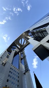 

A low-angle view of a modern Building with glass windows and a circular top structure. Osaka, Japan.