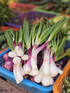 Fresh spring onions with white bulbs and long green leaves arranged in a basket at a local market near Borivali, Mumbai. Their bright colours show natural freshness. 