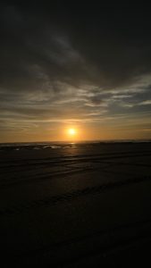 A beautiful sunset over Masachapa Beach, Nicaragua, with warm golden and orange hues spreading across the tranquil shoreline.