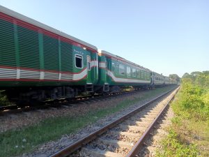 A green coloured train passing through a track and an empty railway track on its side at Kawtoli, Brahmanbaria, Bangladesh