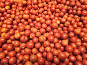 A vibrant collection of red tomatoes arranged in a large pile at a hypermarket in Kozhikode, Kerala. Their bright color and smooth texture show how fresh and ripe they are. 