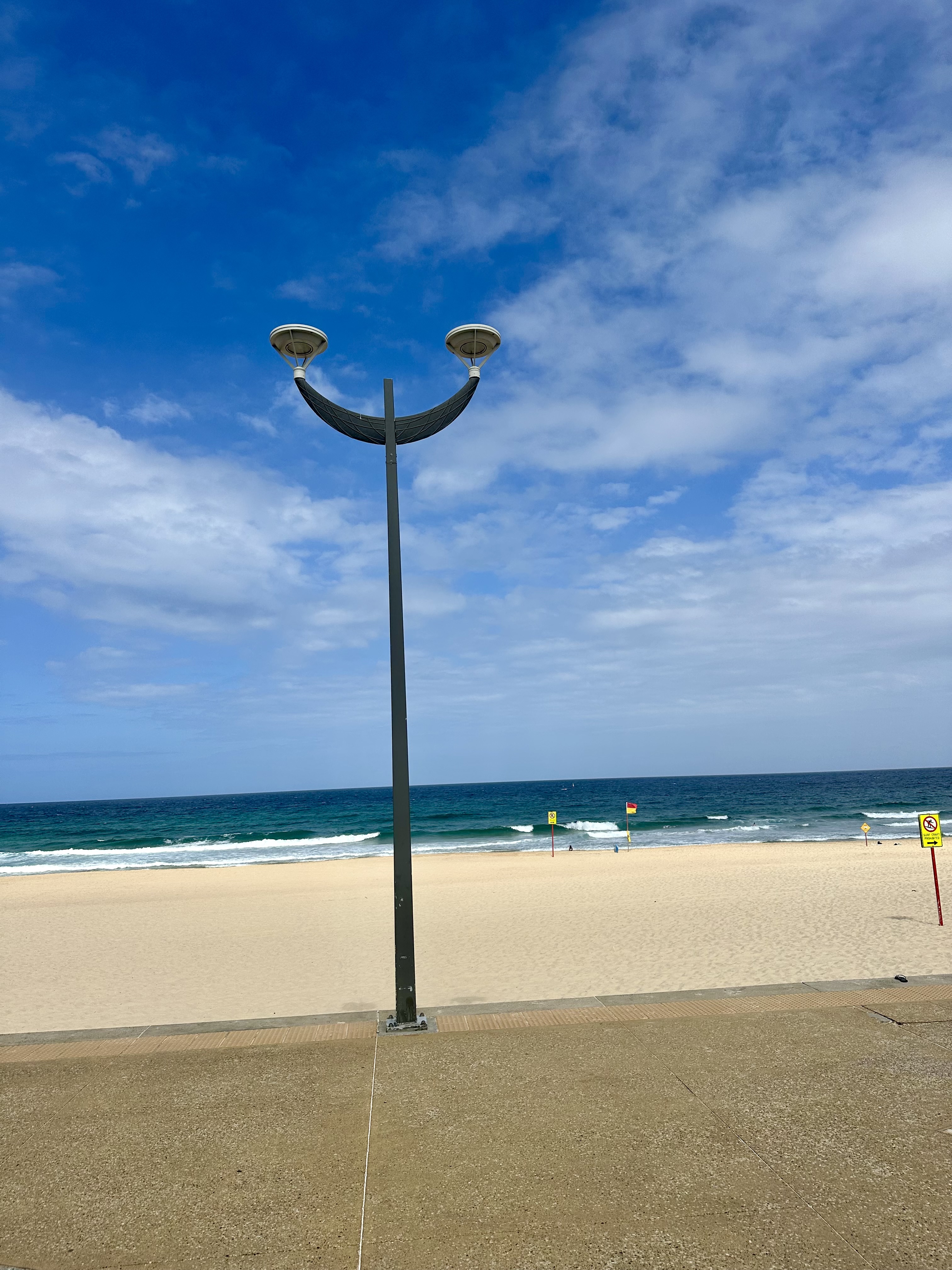 A smiley face depicting lamp post by the sea on a clear blue sky!