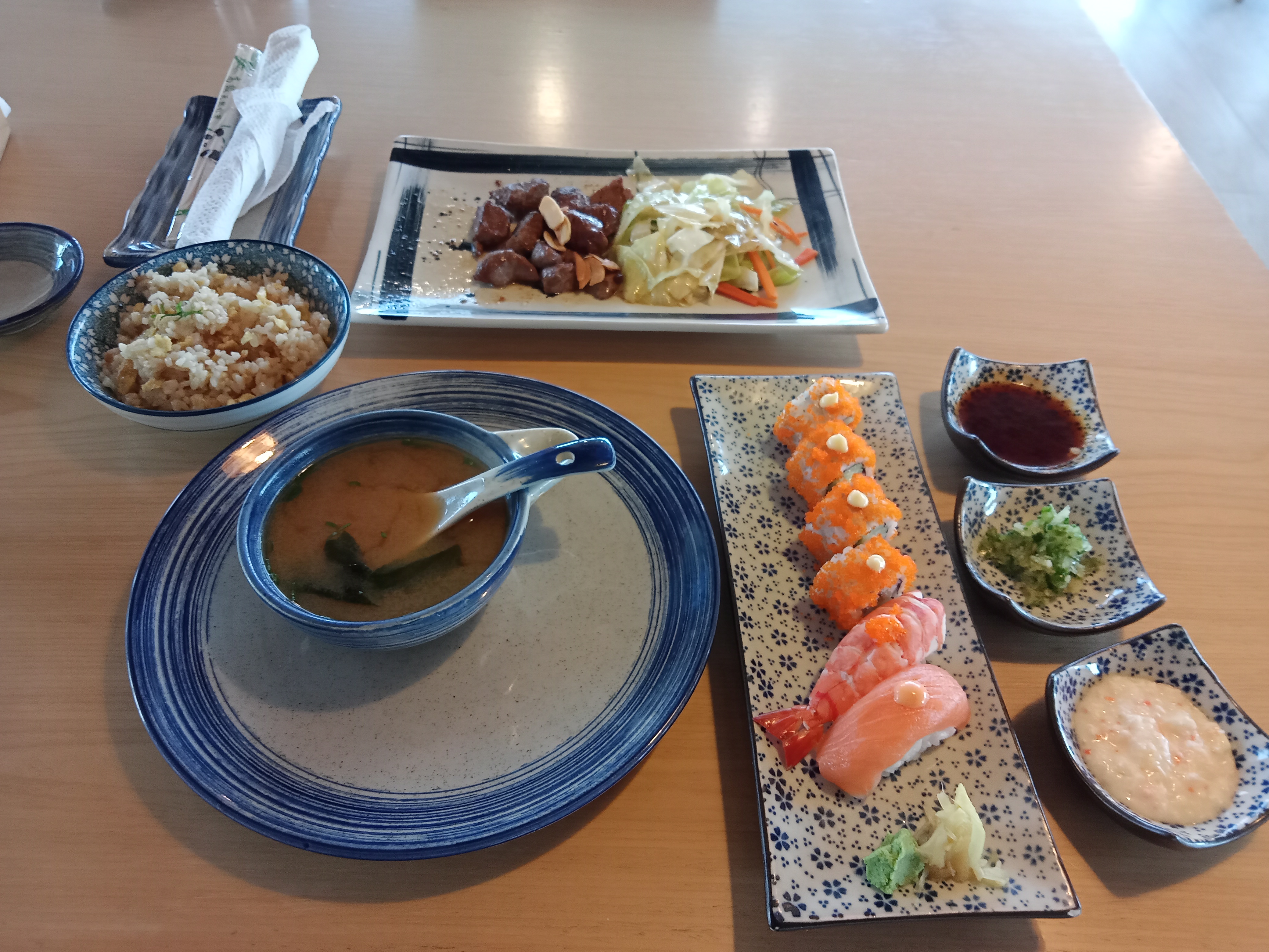 A Japanese meal including beef teppanyaki, maki rolls, and sushi served with ginger and wasabi paste, along with miso soup with tofu, at Izakaya Restaurant in Dhaka, Bangladesh.