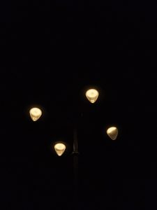 A glowing streetlight shines softly in the night sky over Mumbai, creating a calm, quiet mood.