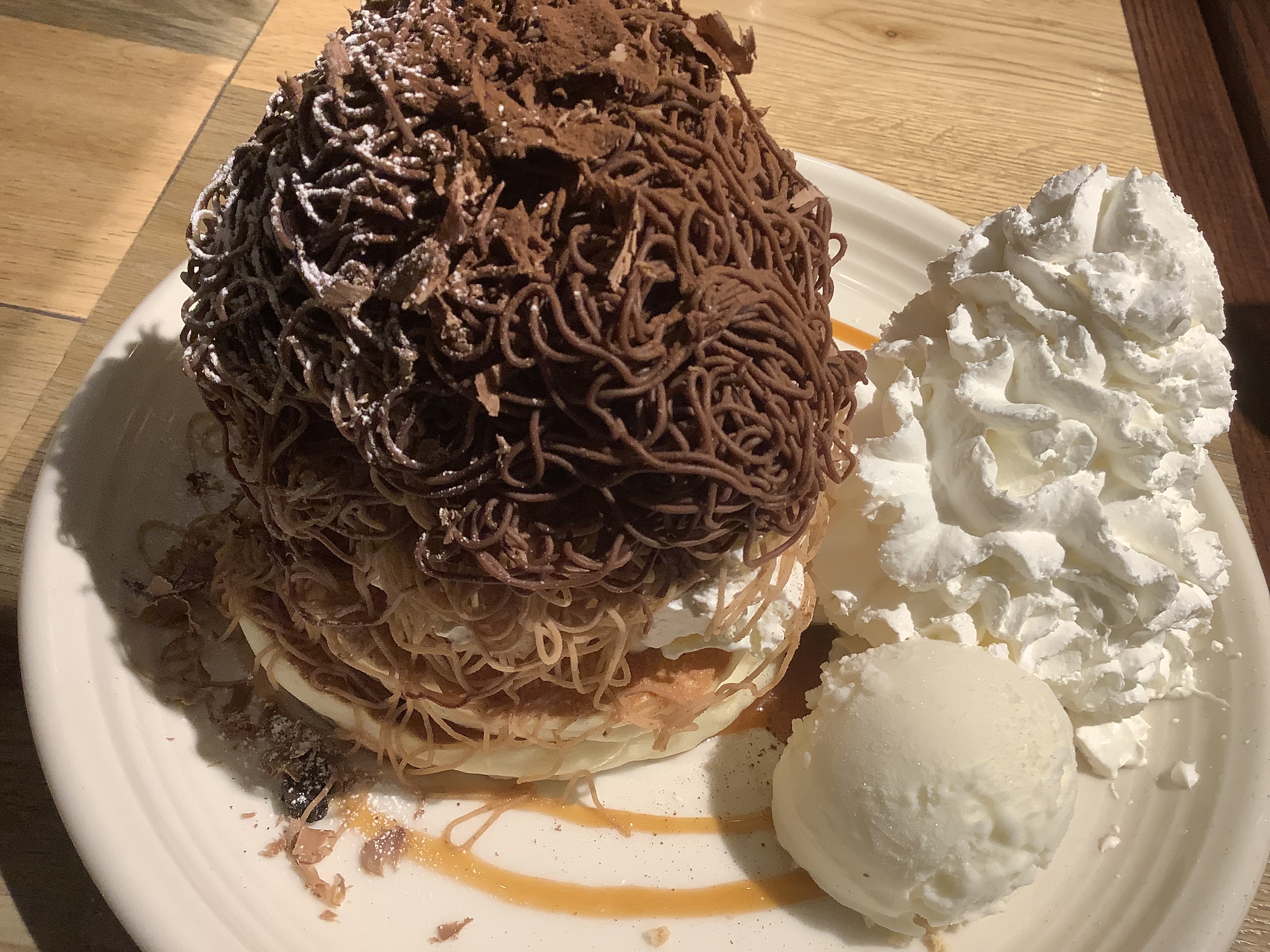 A large dessert featuring a mound of chocolate noodles on top, decorated with chocolate shavings. 