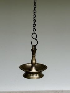 A traditional hanging brass oil lamp (vilakku) is used in Kerala homes and temples. Its antique finish and iron chain add character. Photographed in Perumanna, Kozhikode, Kerala.