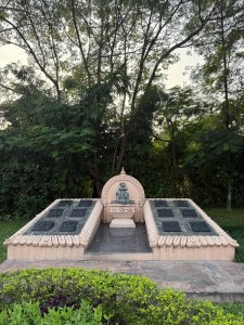 A sculpture of a Hindu god sitting on an elephant made on a cemented floor with tall trees in its background.