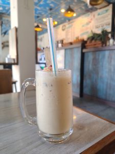 A clear glass mug filled with a creamy beverage sits on a wooden table. 