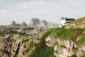 A view looking out across green, sharp mountains with a chalet in the foreground.