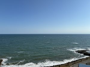 A clear blue sky over a deep blue ocean, with gentle waves and white foam along the shore in Isumi City, Chiba.