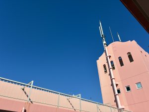 ピンクのマンションの吹き抜けから青空を眺める　/　Gazing at the blue sky from the atrium of the pink apartment building